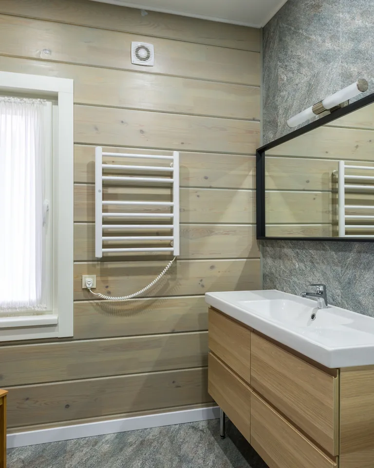 Heated towel rail hanging near a window in a bathroom