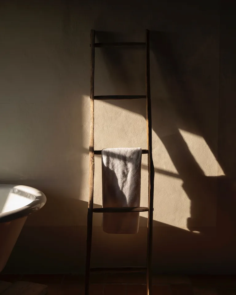 Towel hanging on a rustic wooden ladder in a sunlit bathroom