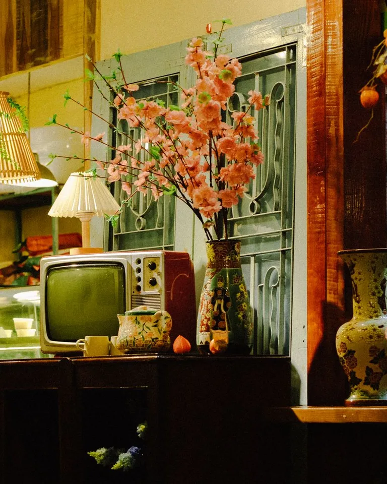 Cozy interior featuring a retro TV, cherry blossoms, and warm lighting
