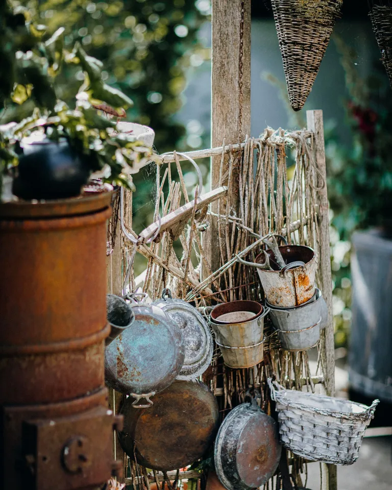 Hanging pots and pans against a weathered fence outdoors