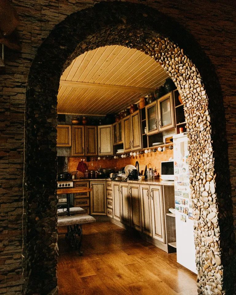 Rustic kitchen interior with wooden cabinetry and a stone archway