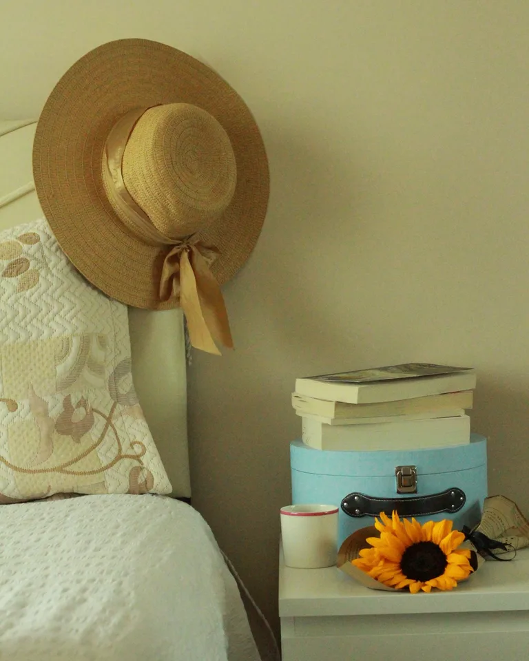 Bedside table styled with stacked books, fresh flowers, and a cup of tea