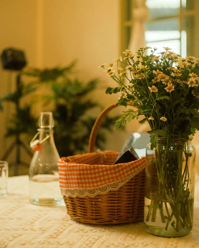 Floral arrangement and picnic basket on a lace-covered table