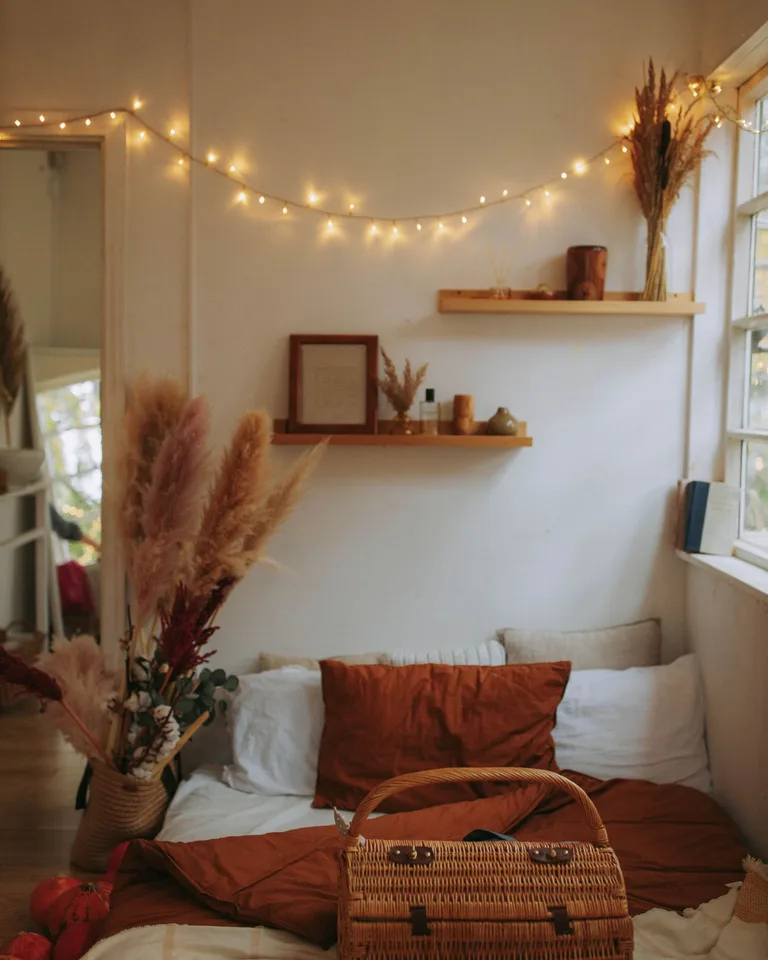 Warm bedroom interior with wicker basket, fairy lights, and pampas grass