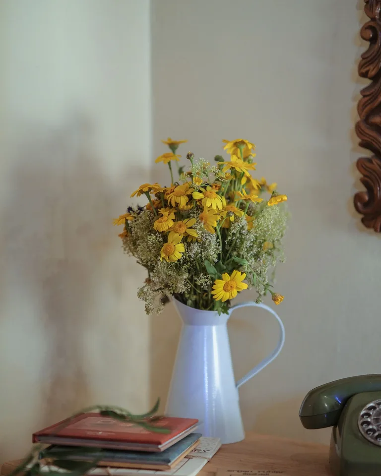 Vase of fresh yellow flowers beside vintage books