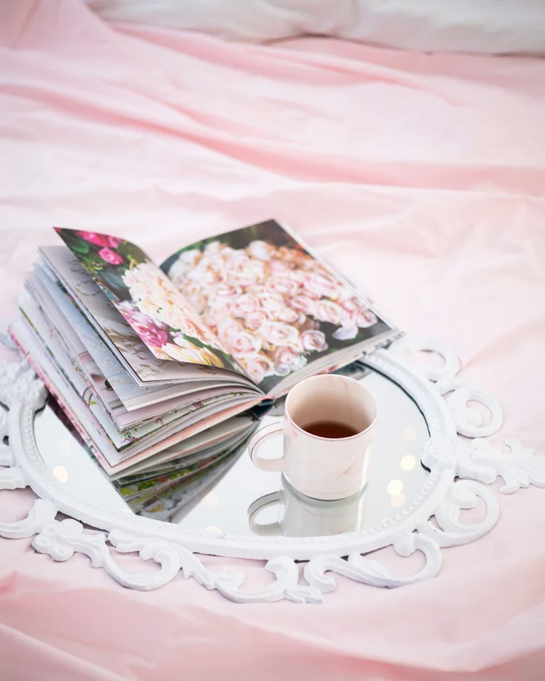 Cup of tea and an open floral book on a decorative tray