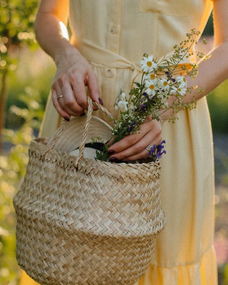 Woman in a yellow dress holding a basket of freshly picked wildflowers