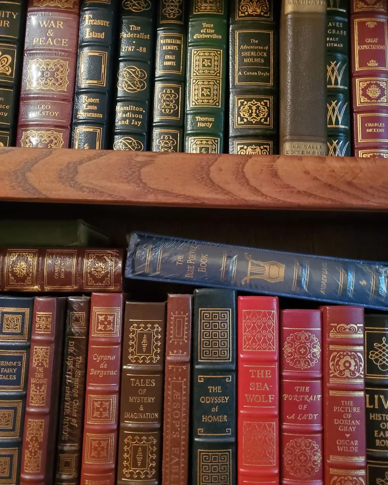 Leather-bound books on a warm wooden shelf