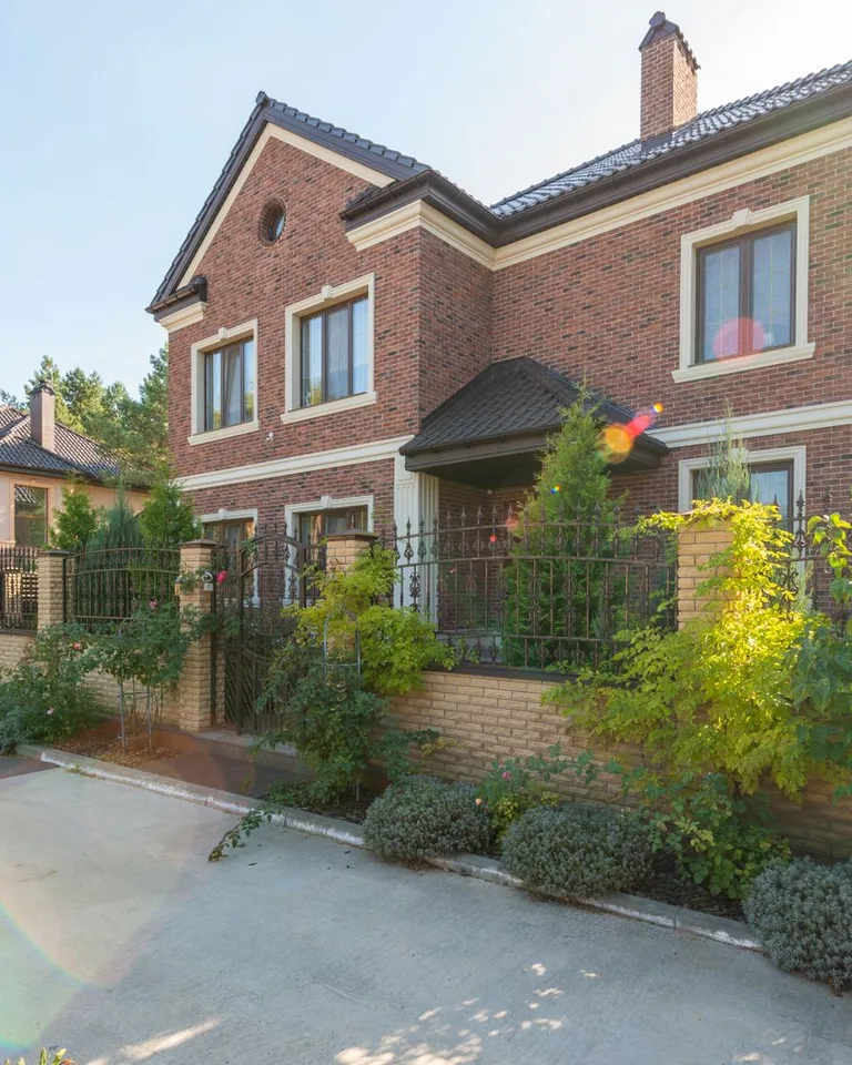 Elegant brick house with a lush garden and driveway