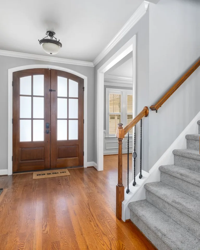 Home foyer with wooden door, staircase, and decor