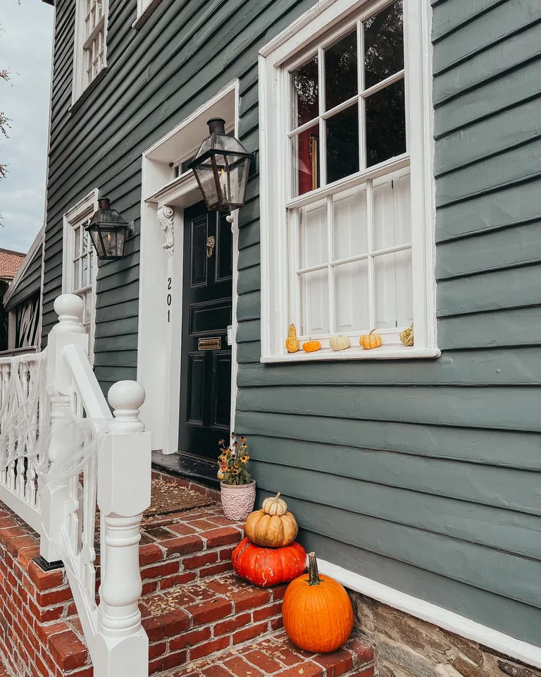 Cozy autumn porch scene with pumpkins, lanterns, and a classic doorway