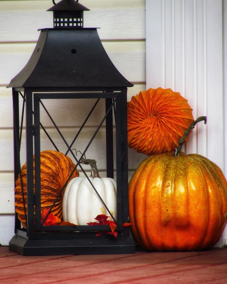 Autumn scene with pumpkins and a lantern on a porch