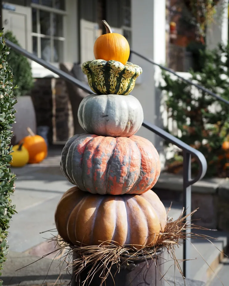 Decorative stack of pumpkins and gourds outside a house