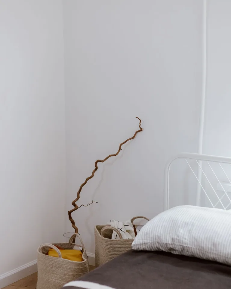 Woven storage baskets tucked under a bed in a small bedroom