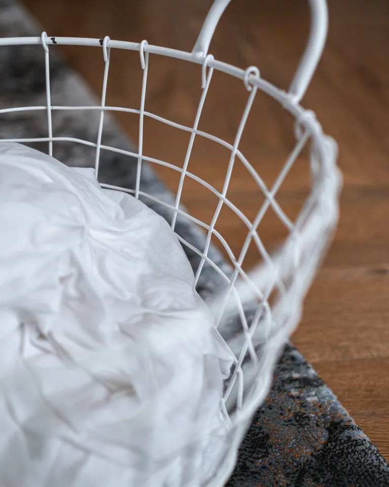 Stylish wire laundry basket in a small bedroom corner