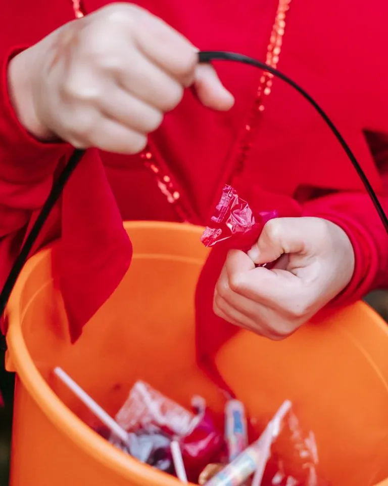 Child holding a Halloween candy bucket full of treats