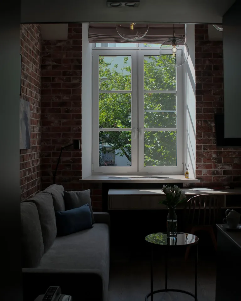 Sunlit room with brick walls, sofa and desk by a large window