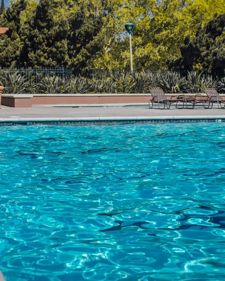 Sparkling blue pool water with empty lounge chairs on the poolside