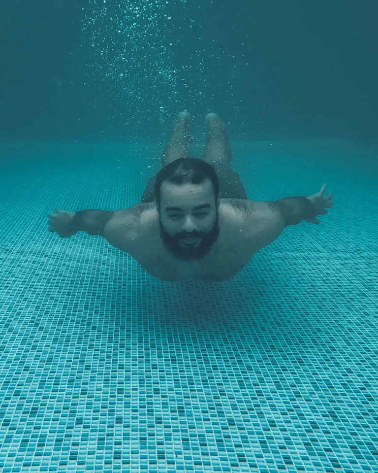 Man swimming underwater in a turquoise pool