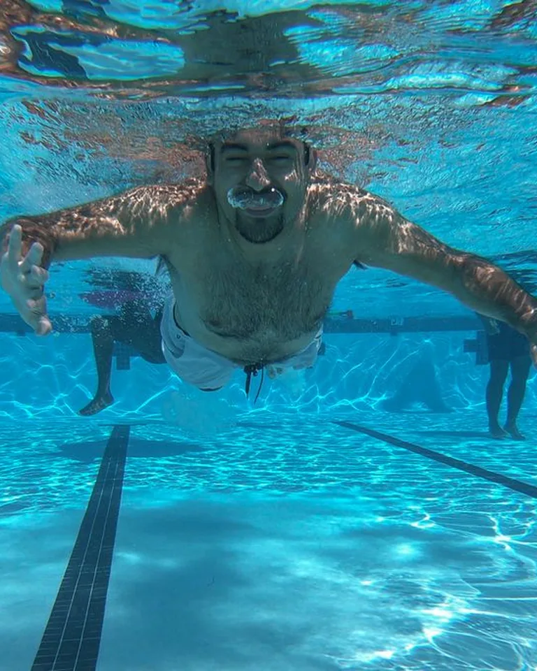 Man swimming underwater in a bright pool on a summer day