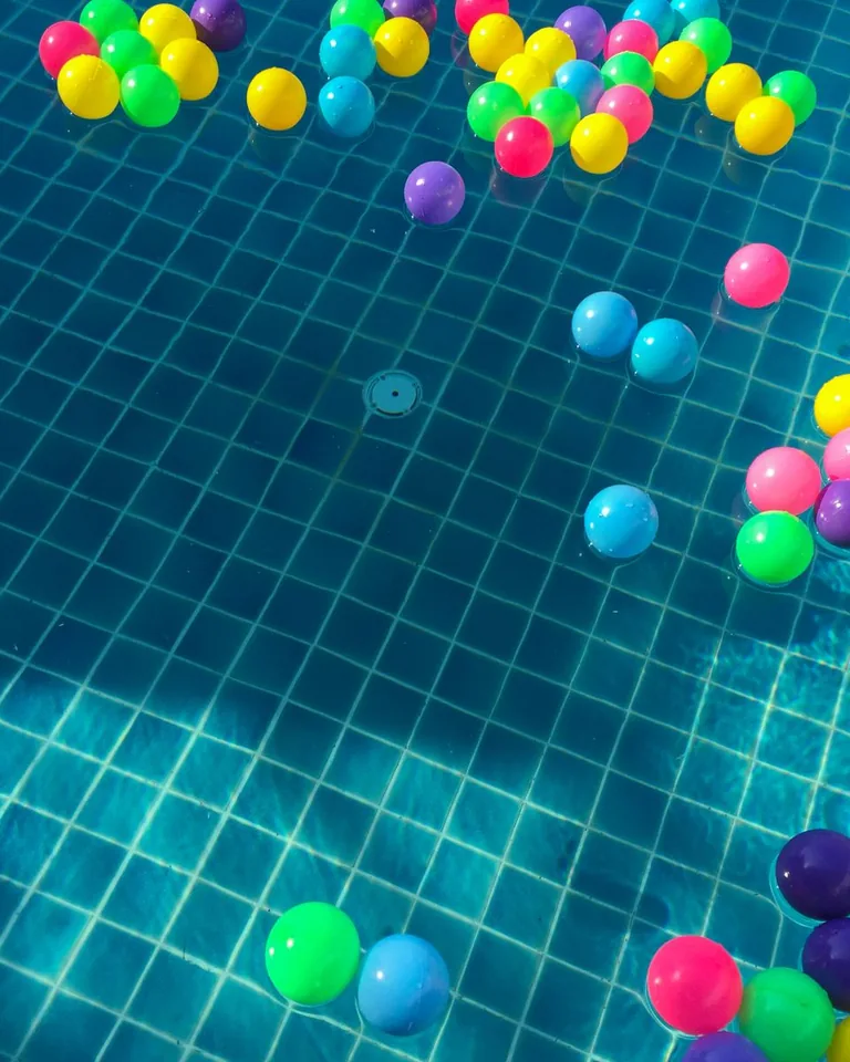 Colorful plastic balls floating in a sunlit swimming pool