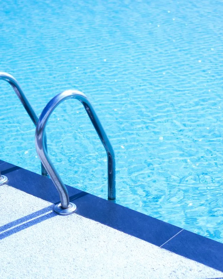 Metal ladder leading into a turquoise swimming pool