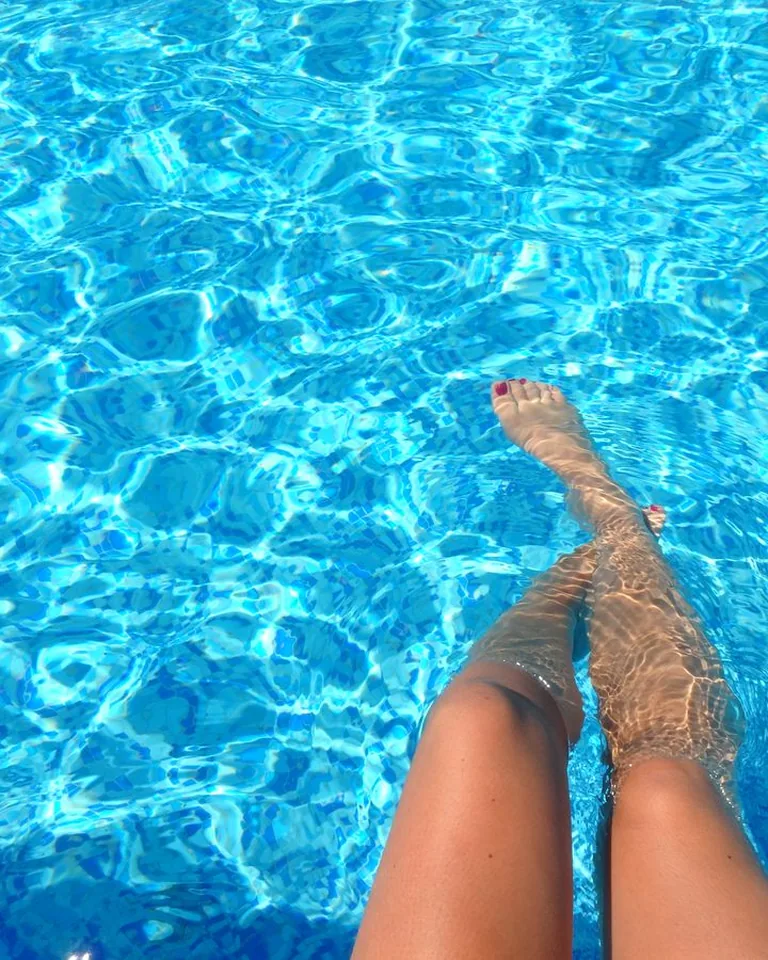 Person relaxing in a swimming pool with clear blue water