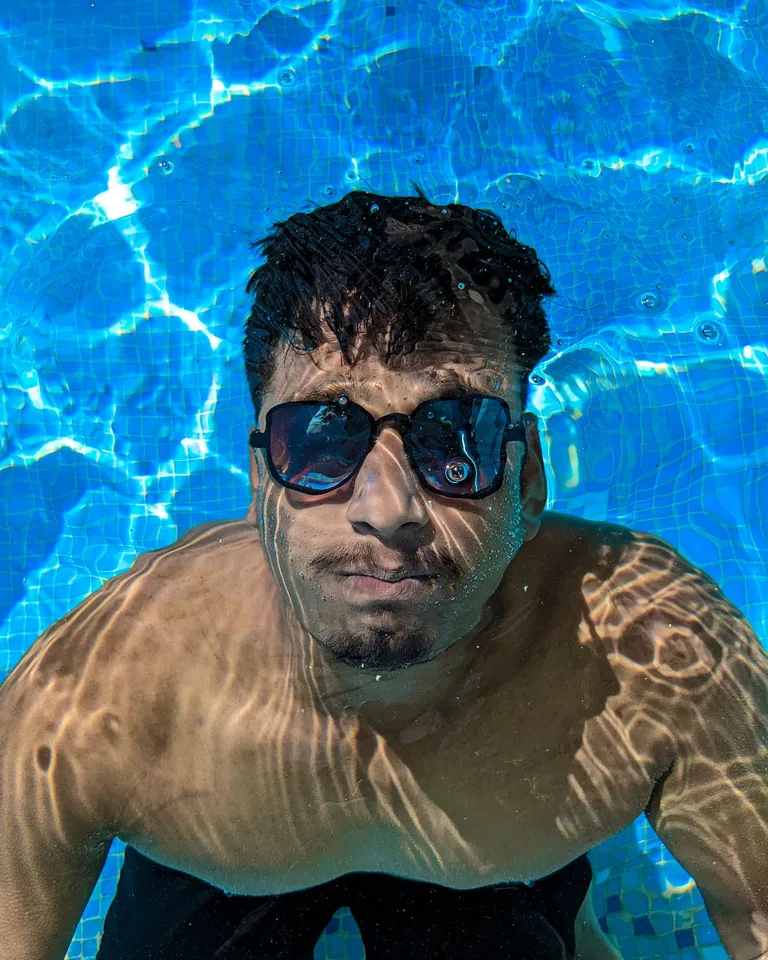 Swimmer underwater wearing sunglasses in a pool
