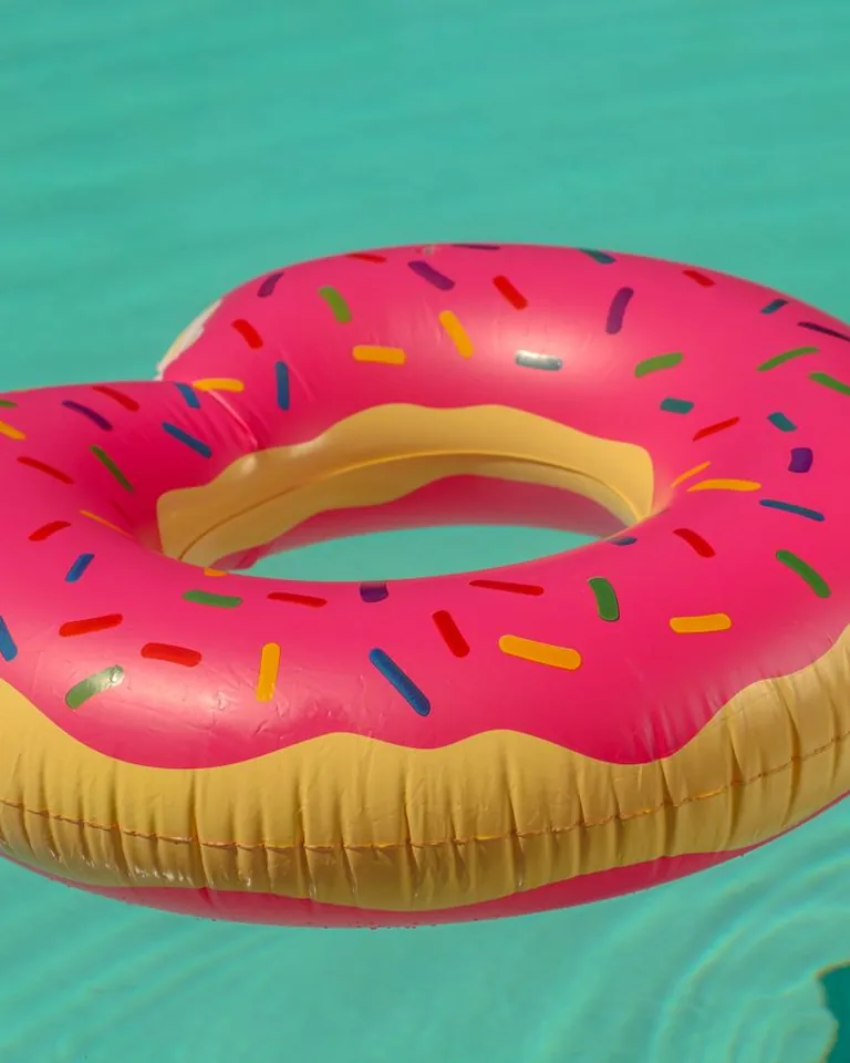 Pink inflatable donut floater on clear blue water