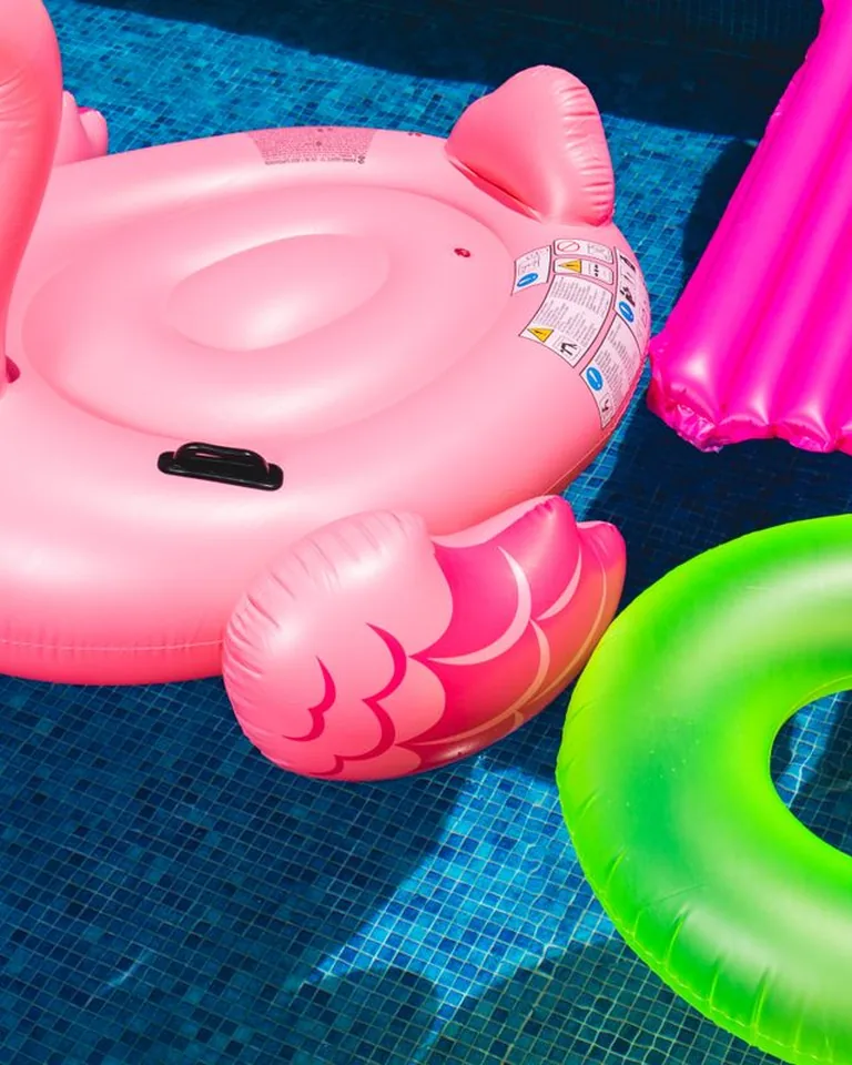 Pink flamingo and green inflatable rings on a swimming pool