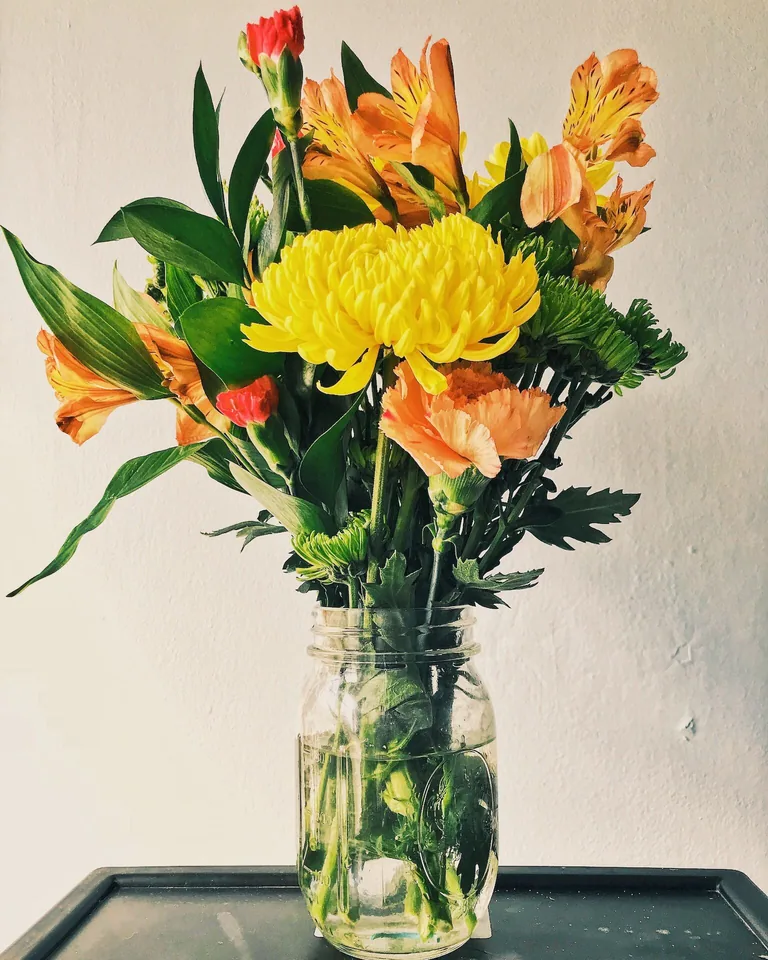 Yellow mums and orange flowers in an autumn arrangement