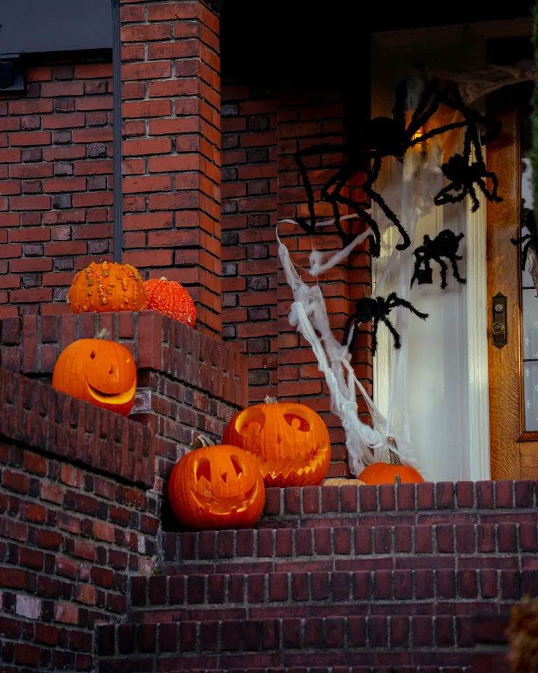 House entrance decorated with pumpkins on a brick porch