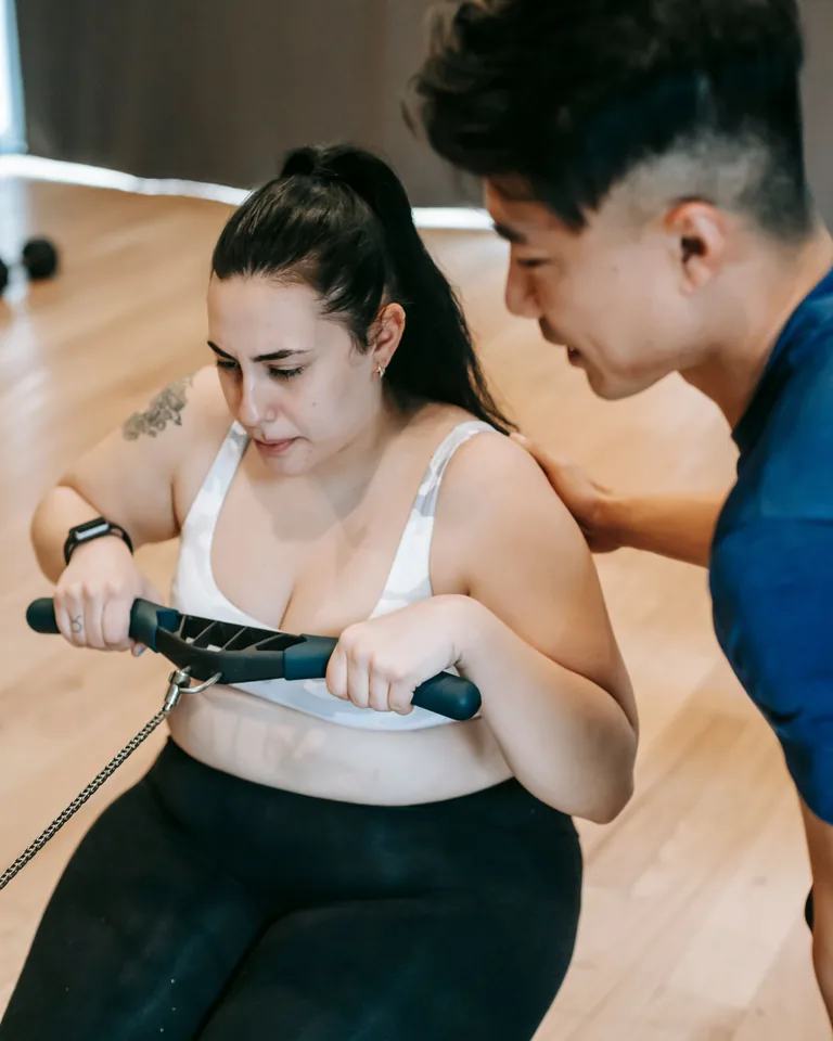 Woman exercising on a rowing machine with trainer guidance