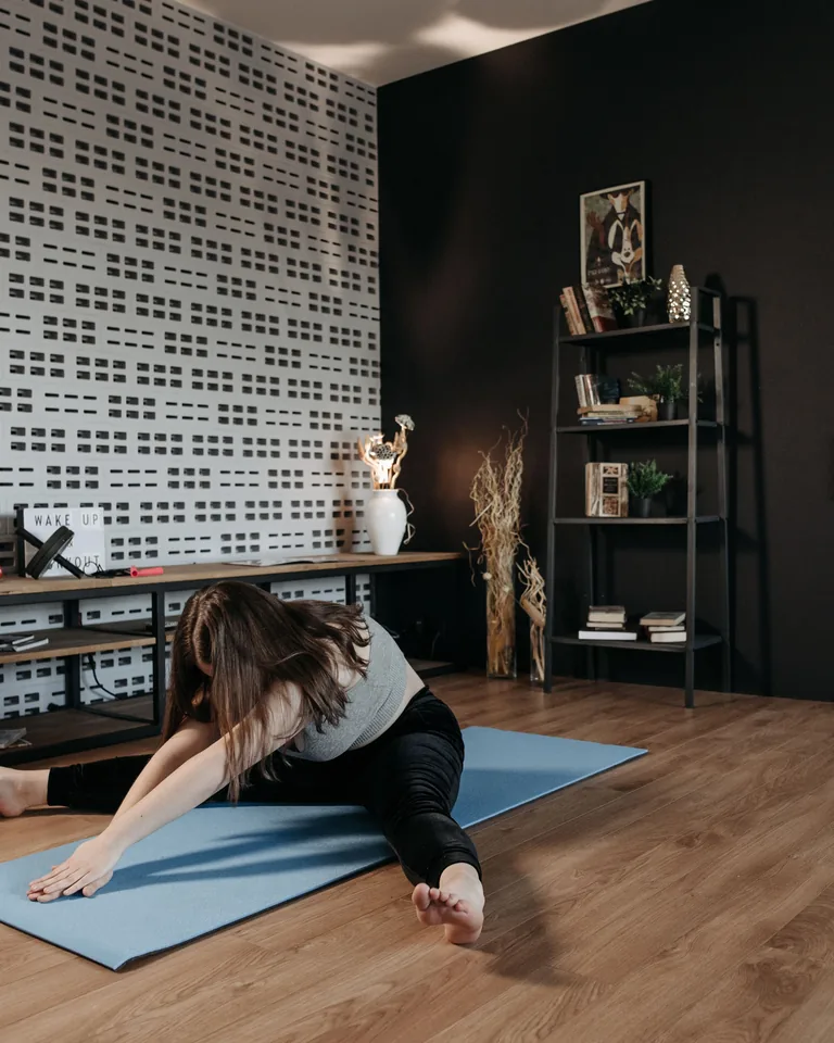 Woman doing stretching exercise on a yoga mat indoors