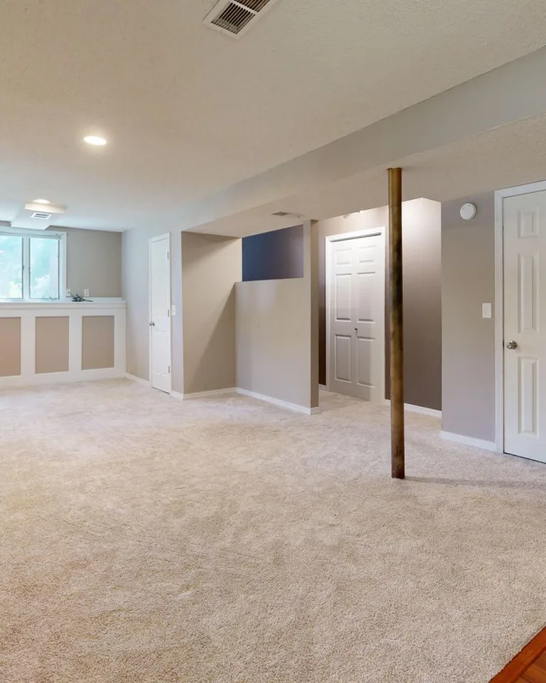 Bright and clean modern basement with carpet flooring and recessed lighting