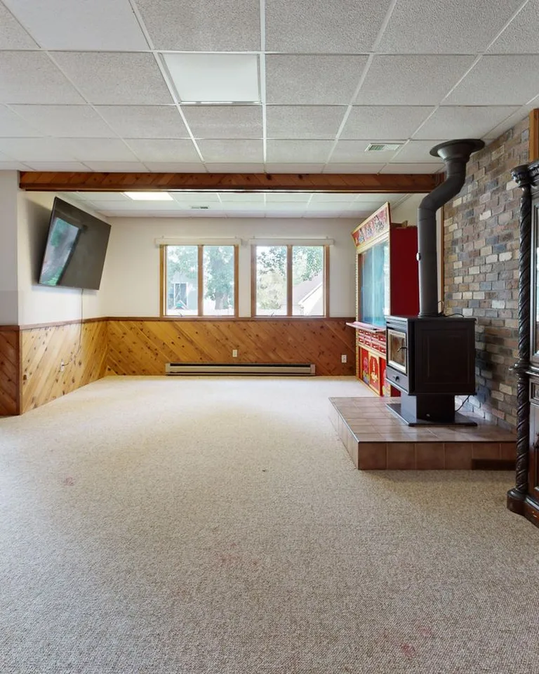 Cozy basement with wooden paneling, fireplace and sunny windows