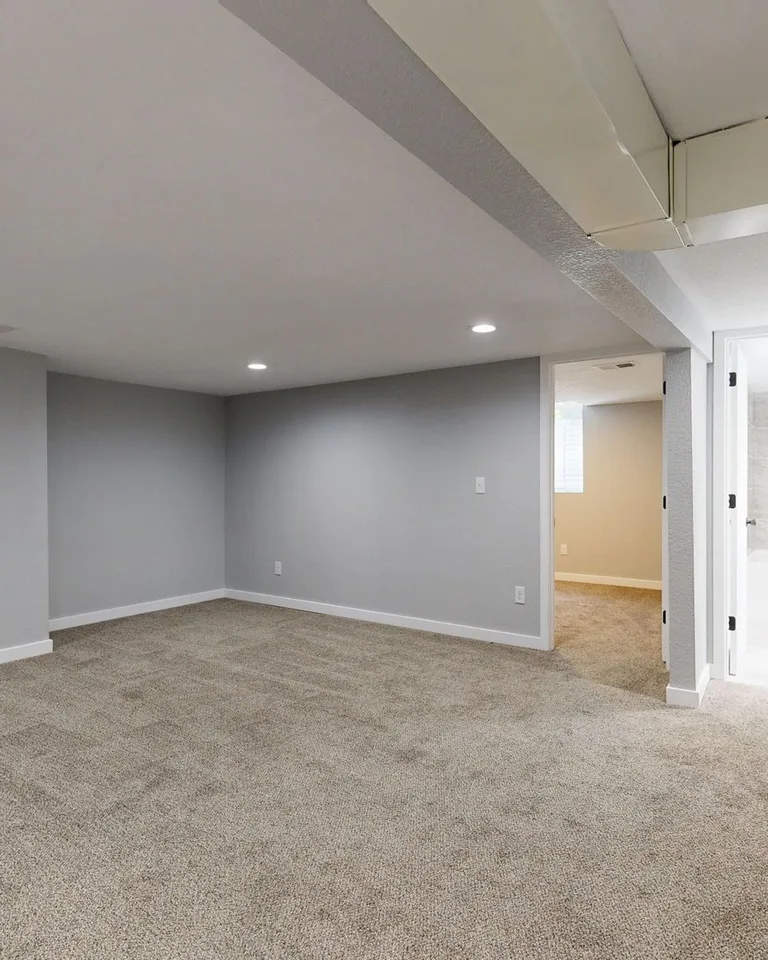 Empty basement room with neutral carpet and recessed lighting