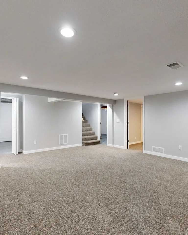 Spacious modern basement with neutral design and carpet flooring