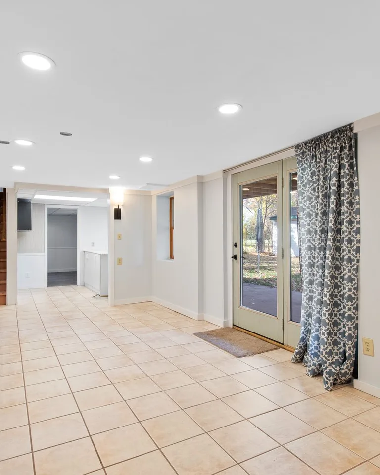 Bright basement with tile flooring and glass doors leading outside