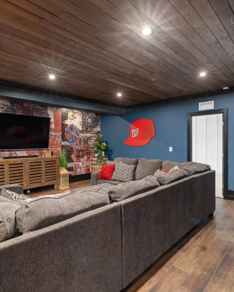 Spacious basement room with stylish decor, large couch and TV setup