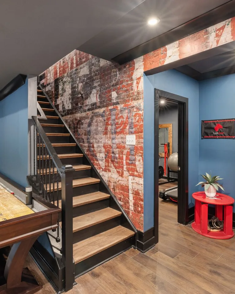 Modern basement interior with game table, rustic brick walls and a stairway