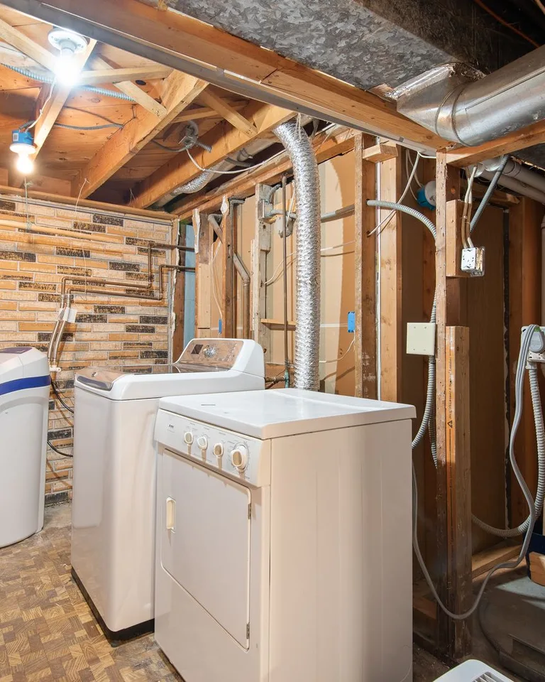 Spacious basement laundry room with modern appliances and exposed brickwork