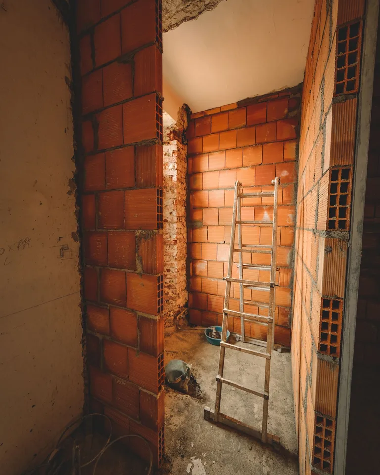 Ladder leaning against red brick walls during a renovation