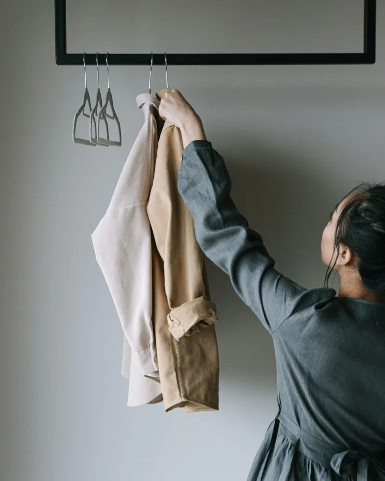Woman holding clothes on a hanger while decluttering