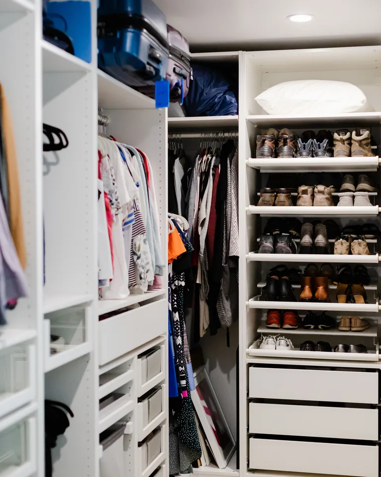 Well-organized walk-in closet with clothes and shoes on shelves