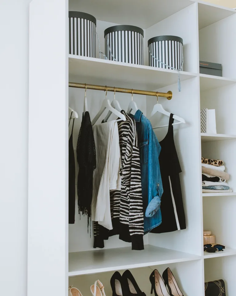 Clothes arranged on a white wooden cabinet with shelves