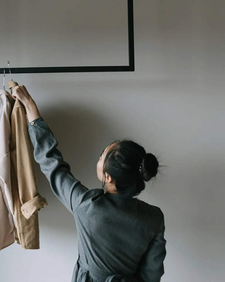 Woman reaching for clothes on a minimalist rack