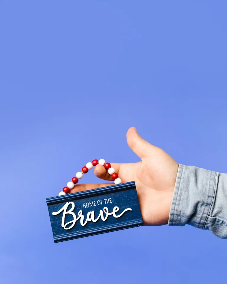 Wooden Home of the Brave sign on blue