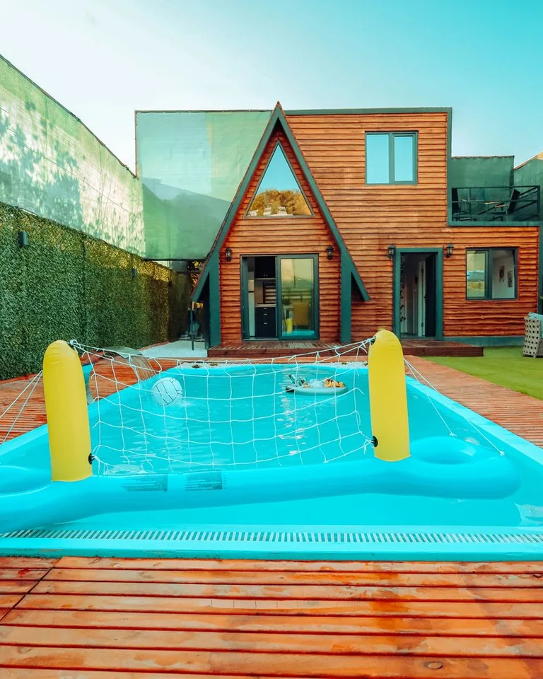 Spacious backyard with a wooden house and swimming pool with an inflatable net