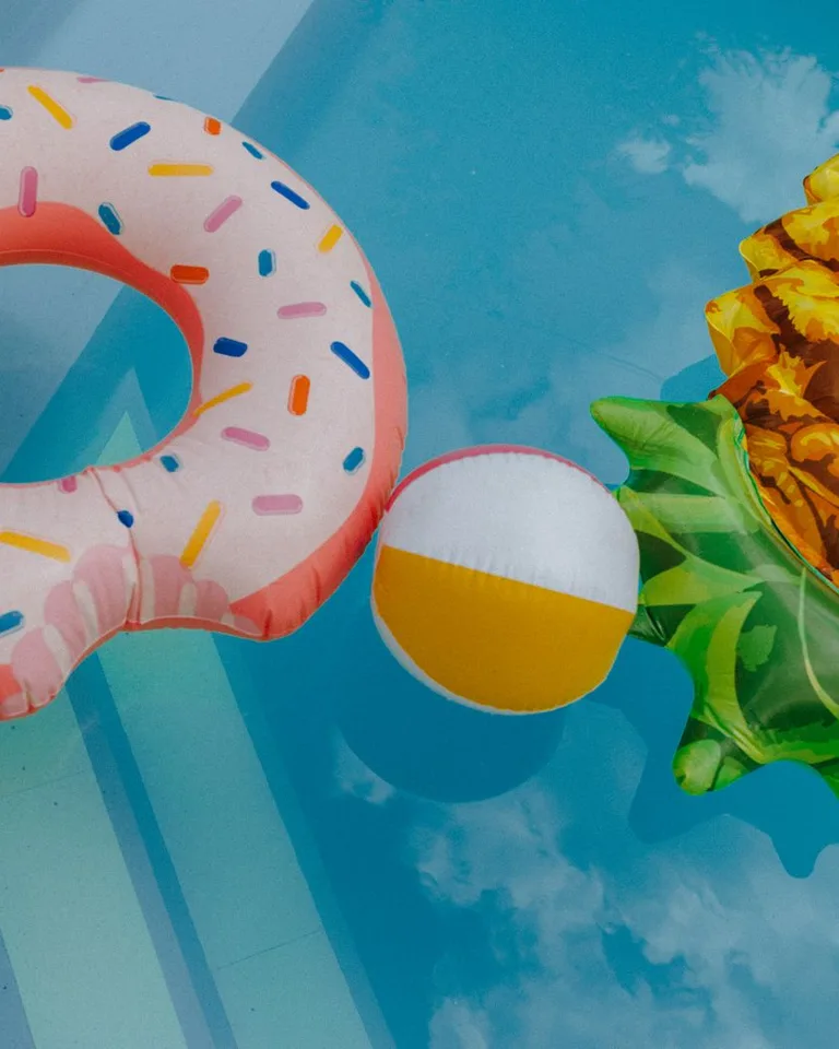 Colorful pool floats and a beach ball in a clear swimming pool